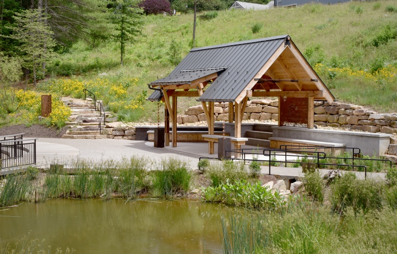 A pond with a wooden picnic shelter on the far side