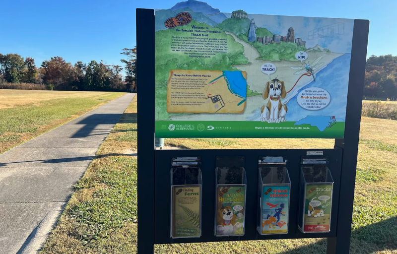 Photo of the TRACK Trail kiosk next to a paved trail
