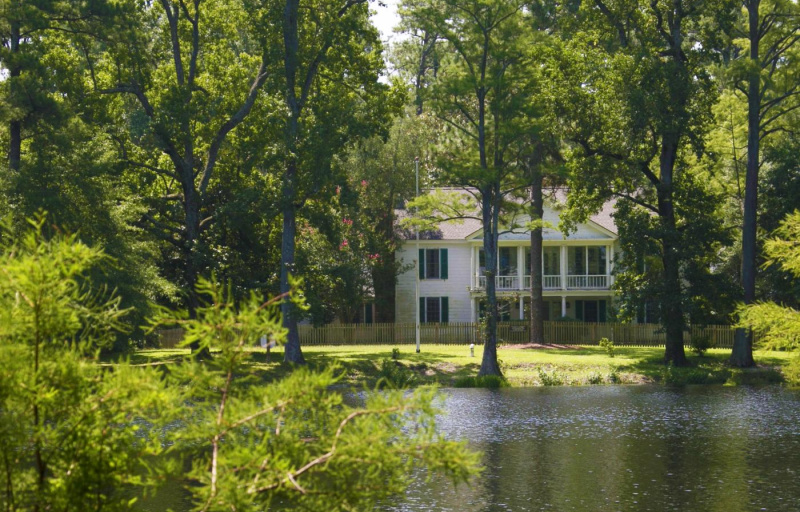 A view of a large, white historical home across the water