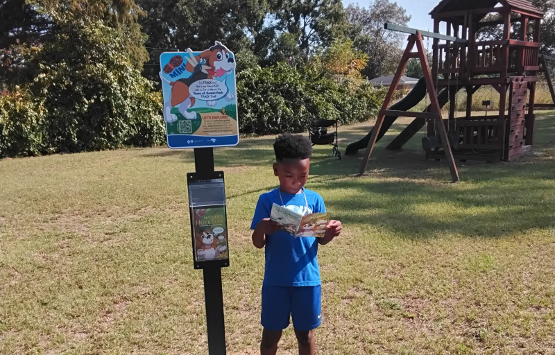 Child holding brochure at mini sign