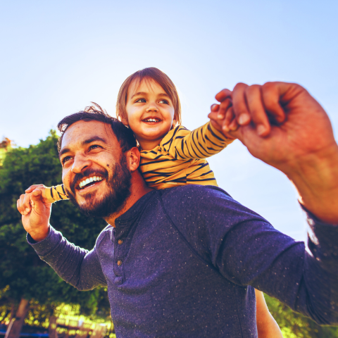 A child riding on their father's back while enjoying the outdoors