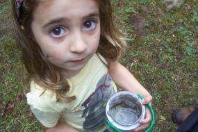 Young girl holding a bucket with a crayfish inside
