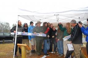 Ribbon cutting ceremony underneath pop up tent in a light rain 