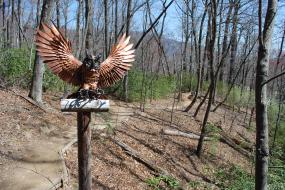 Wooden owl perched on a wooden trail marker