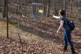 Disc golfer putting a disc into a basket