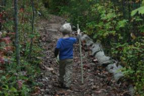 Young boy on trail with walking stick