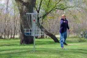 man throwing disc at disc golf basket