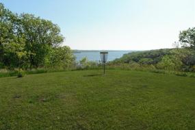 a disc golf basket with big stone lake in the background