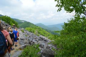 Group of kids hiking through a rock field on the side of a mountain