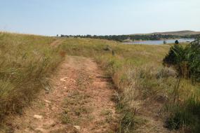 trail though a meadow with the reservoir in the background