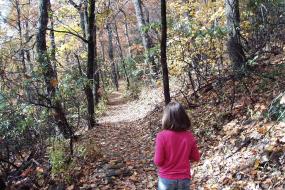 Young girl walking on  trail in fall