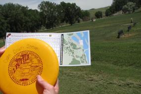 close up of someone holding a yellow disc with red writing and a scorecard