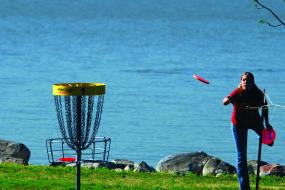 woman throwing a disc at the basket for hole 1