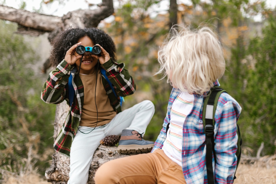 One child looks at another child through binoculars