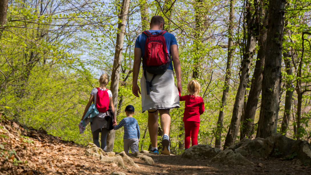 a family of four hiking on a gravel dirt trail in the spring